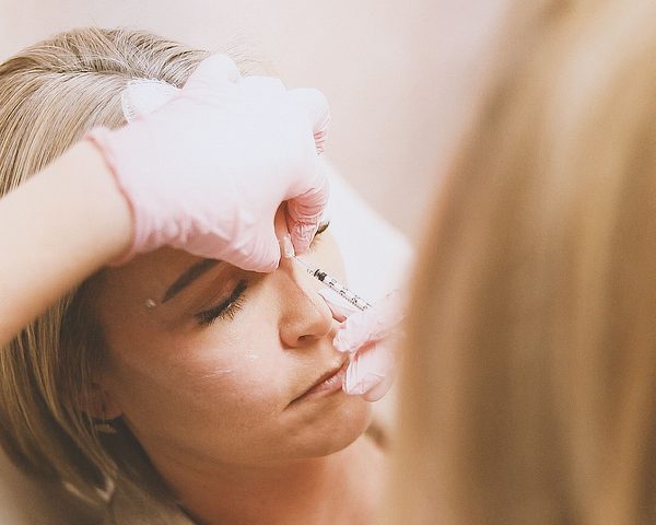 Dermal filler applied with a fine needle to the mid-face area — illustrative image